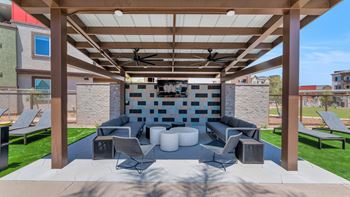 A covered patio with couches and chairs and a fireplace
